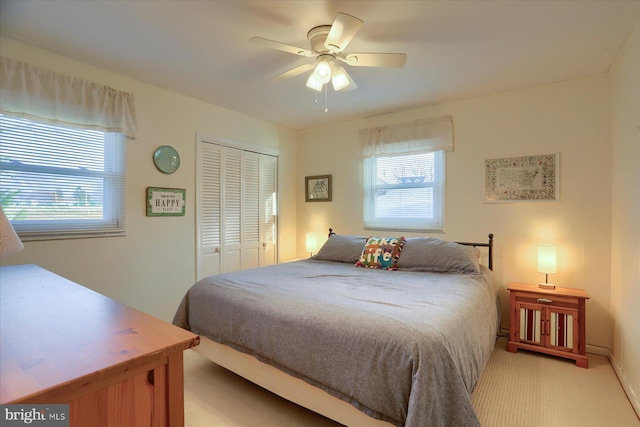 bedroom featuring ceiling fan, light carpet, and a closet