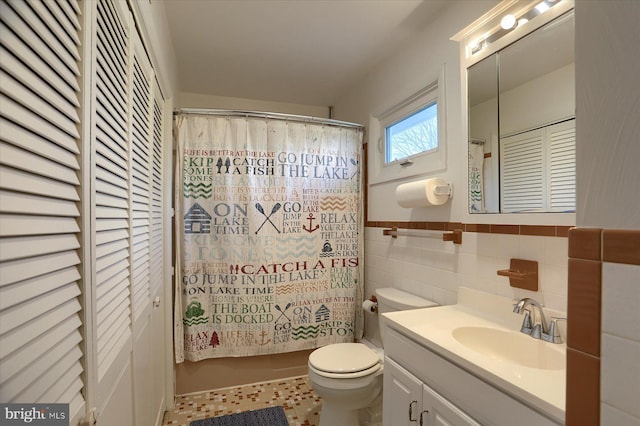 bathroom featuring tile patterned floors, vanity, tile walls, and toilet