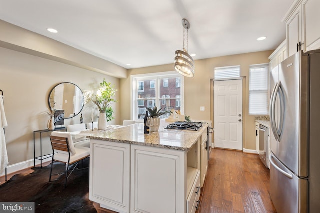 kitchen with dark wood-type flooring, hanging light fixtures, a kitchen island, white cabinetry, and stainless steel appliances