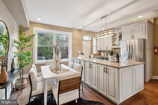 kitchen featuring light stone countertops, dark hardwood / wood-style flooring, a center island, and pendant lighting