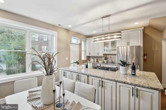 kitchen featuring a center island, decorative light fixtures, white cabinetry, wood-type flooring, and stainless steel appliances