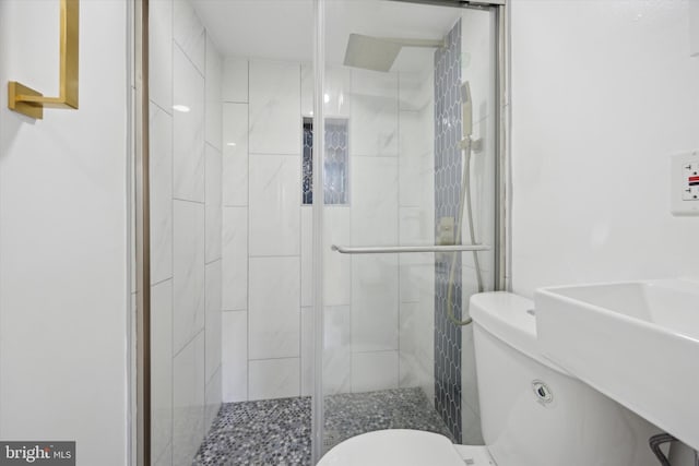 bathroom with toilet, a shower with shower door, and sink