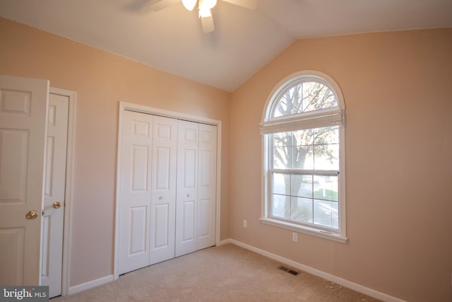 unfurnished bedroom featuring light carpet, vaulted ceiling, and ceiling fan