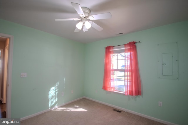 empty room with electric panel, ceiling fan, and light colored carpet