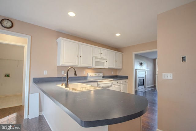 kitchen with kitchen peninsula, white appliances, white cabinetry, and sink