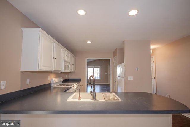 kitchen featuring white cabinets, sink, white appliances, and kitchen peninsula