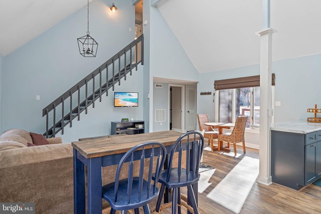 dining room with hardwood / wood-style flooring, high vaulted ceiling, and a chandelier