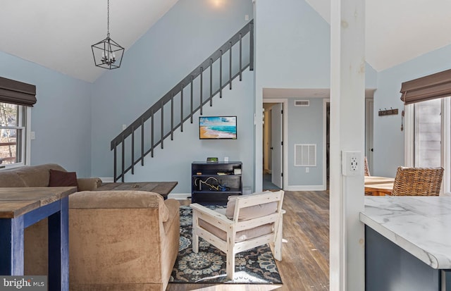 living room featuring a notable chandelier, wood-type flooring, and high vaulted ceiling