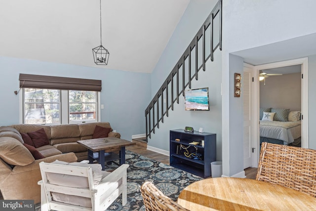 living room featuring high vaulted ceiling, ceiling fan with notable chandelier, and hardwood / wood-style flooring