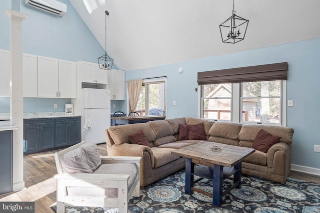 living room featuring a wall unit AC, light hardwood / wood-style flooring, high vaulted ceiling, and an inviting chandelier