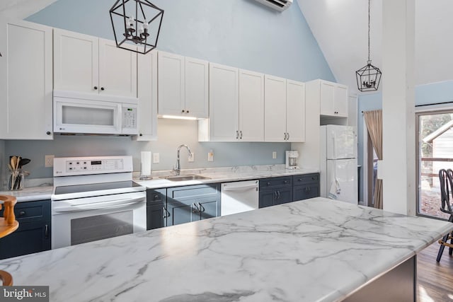 kitchen featuring white appliances, white cabinetry, hanging light fixtures, and sink