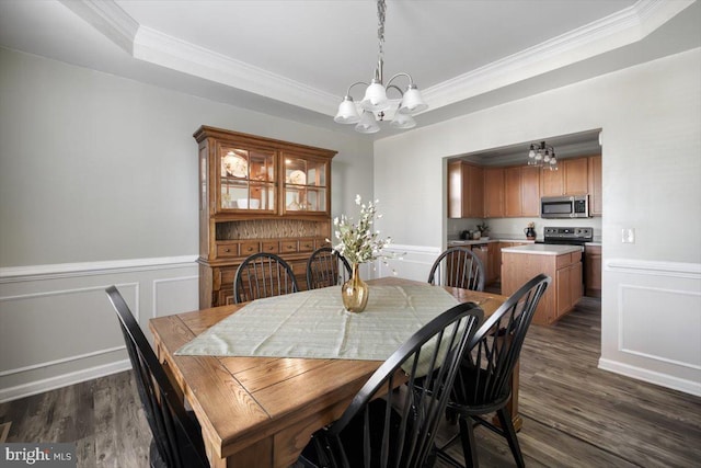 dining room featuring a raised ceiling, ornamental molding, dark wood-type flooring, and a chandelier