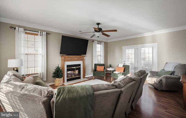 living room featuring a healthy amount of sunlight, dark hardwood / wood-style flooring, ornamental molding, and a high end fireplace