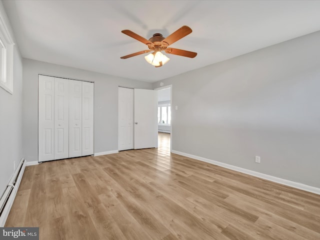 unfurnished bedroom featuring ceiling fan, multiple closets, baseboard heating, and light hardwood / wood-style flooring