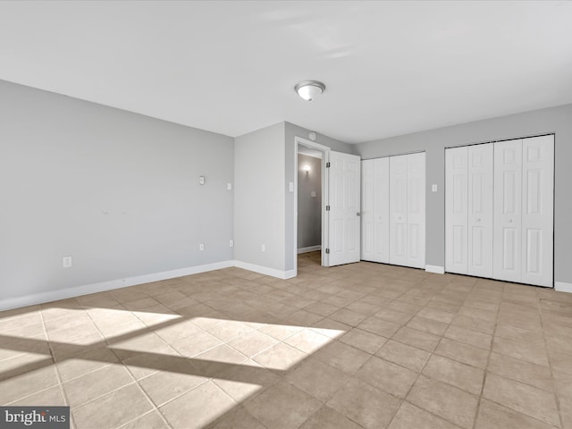 unfurnished bedroom featuring light tile patterned floors and two closets