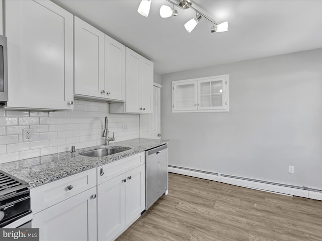 kitchen with light wood-type flooring, light stone counters, stainless steel dishwasher, sink, and white cabinets