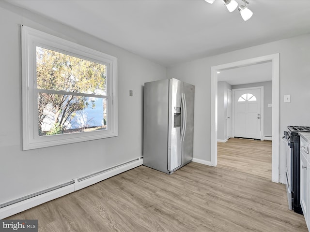 kitchen with baseboard heating, white cabinets, light hardwood / wood-style floors, and appliances with stainless steel finishes