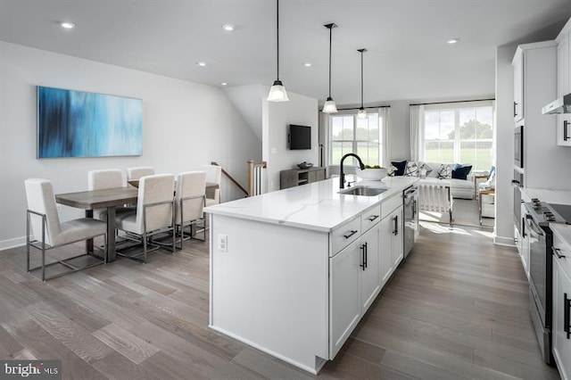 kitchen with white cabinets, an island with sink, and decorative light fixtures