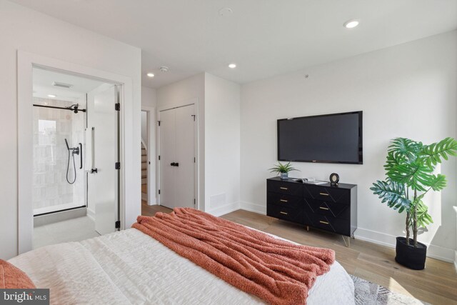 bedroom with connected bathroom and light hardwood / wood-style floors