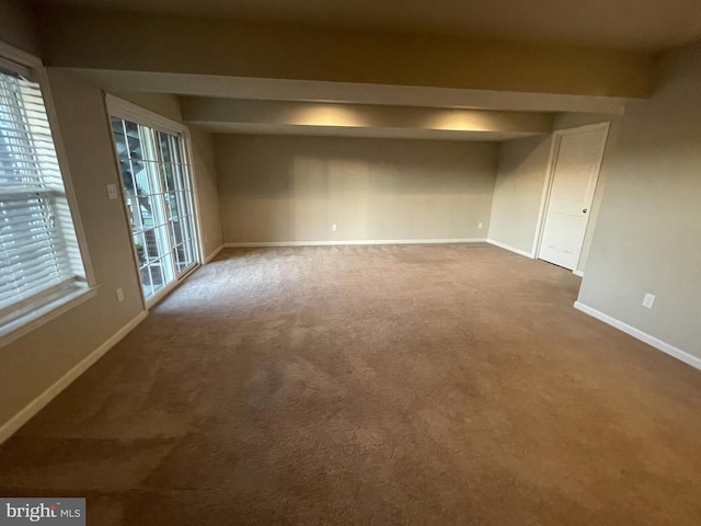 empty room with dark colored carpet and a wealth of natural light