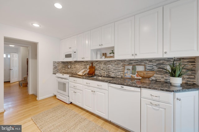 kitchen featuring white appliances, light wood finished floors, a sink, white cabinetry, and backsplash