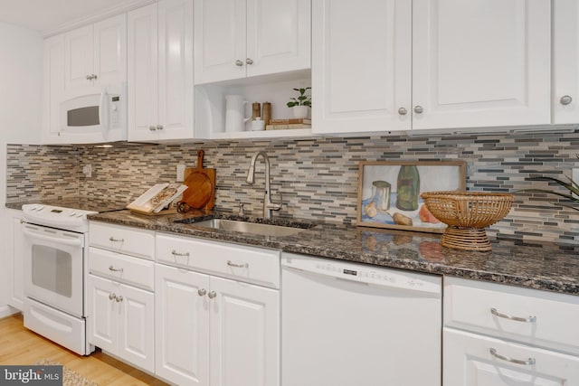 kitchen featuring white appliances, white cabinets, dark stone countertops, open shelves, and a sink