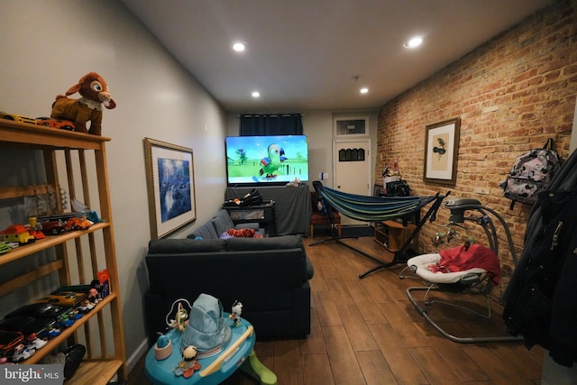 game room featuring wood-type flooring and brick wall