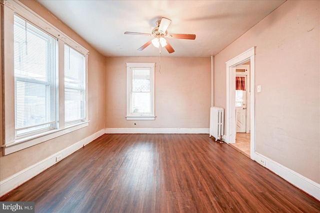 spare room featuring dark hardwood / wood-style floors, ceiling fan, and radiator