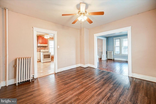 empty room featuring dark hardwood / wood-style floors, ceiling fan, and radiator