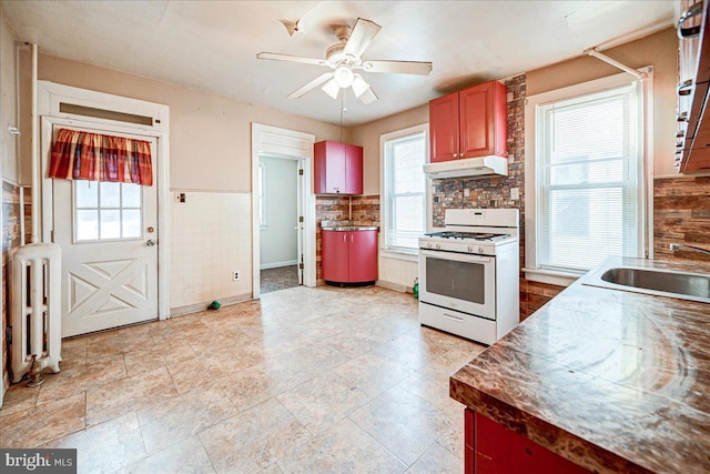 kitchen featuring radiator, ceiling fan, white range with gas cooktop, and sink