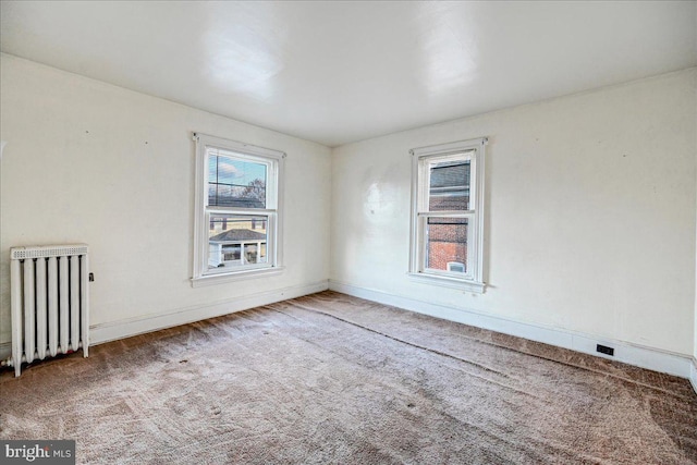 empty room featuring radiator and carpet floors