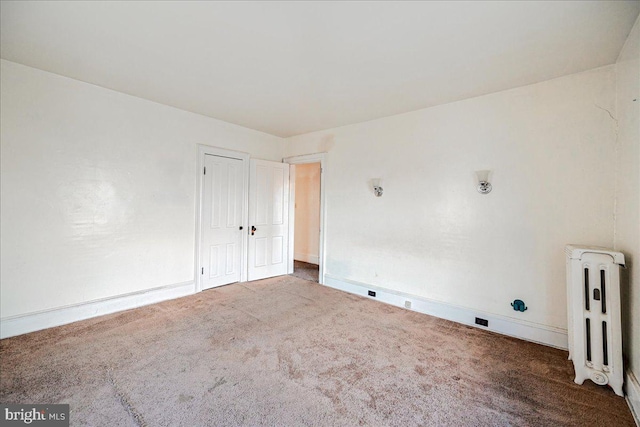 spare room featuring radiator and carpet