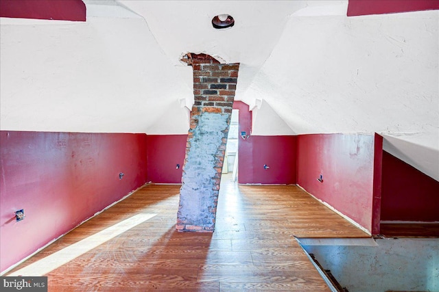 bonus room with hardwood / wood-style floors and vaulted ceiling