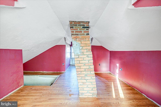 bonus room with hardwood / wood-style floors and vaulted ceiling