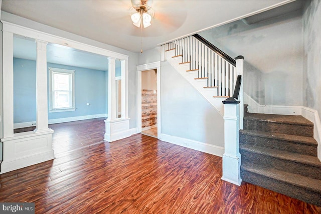 stairway with decorative columns, ceiling fan, and wood-type flooring