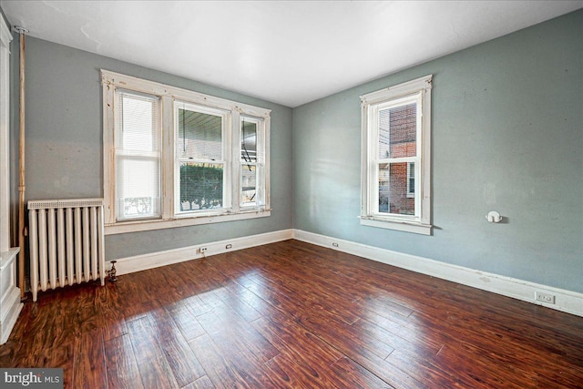 spare room featuring dark hardwood / wood-style flooring and radiator