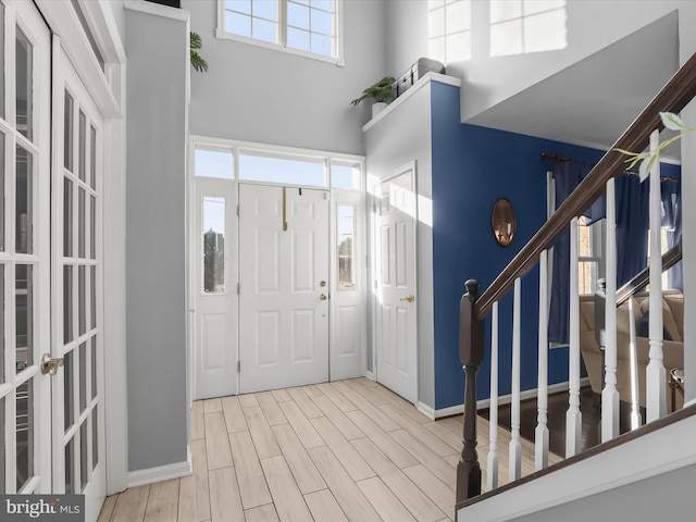 entryway featuring light wood-type flooring, a high ceiling, and a wealth of natural light