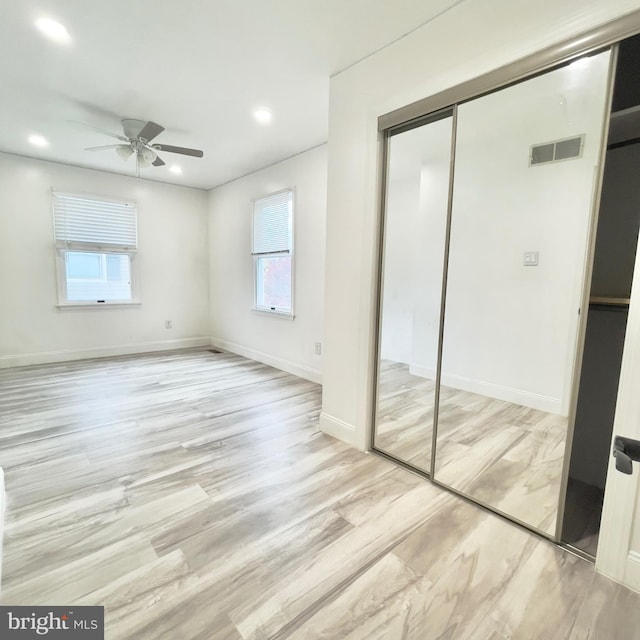 unfurnished bedroom featuring ceiling fan, light wood-type flooring, and a closet