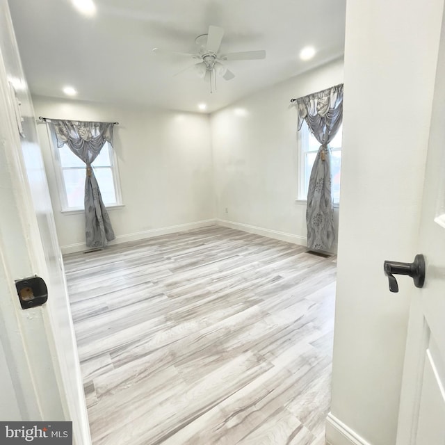 spare room with ceiling fan, a healthy amount of sunlight, and light wood-type flooring