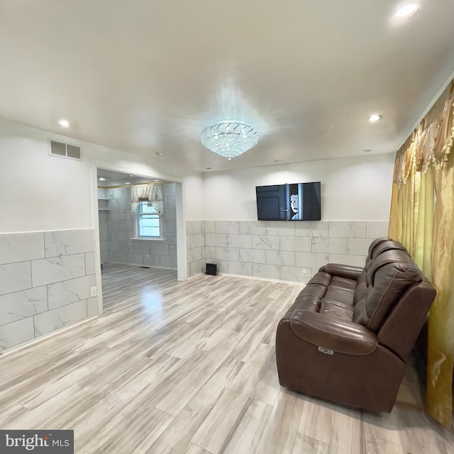 living room featuring light hardwood / wood-style floors and tile walls