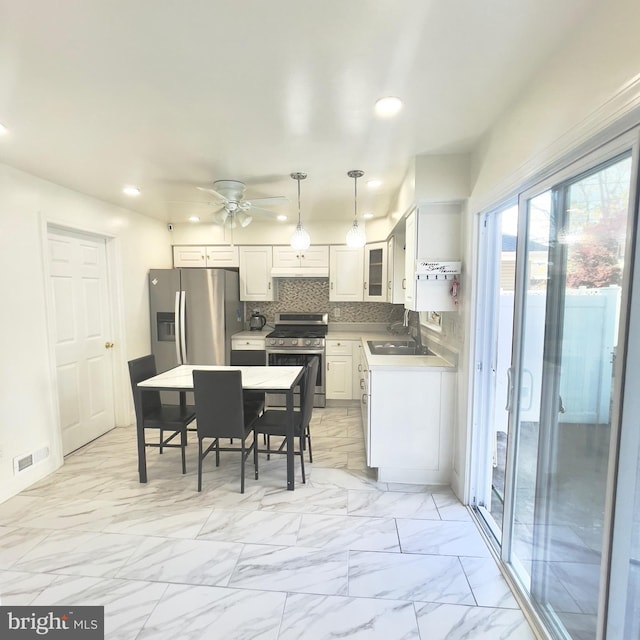 kitchen with decorative backsplash, stainless steel appliances, sink, decorative light fixtures, and white cabinetry