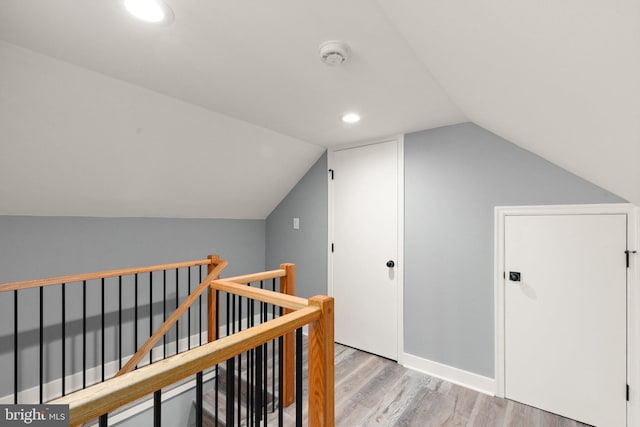 hallway with light hardwood / wood-style floors and vaulted ceiling