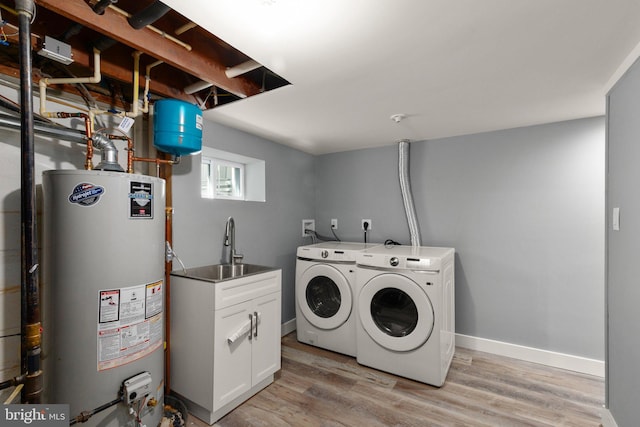 clothes washing area with washing machine and clothes dryer, light wood-type flooring, sink, and water heater