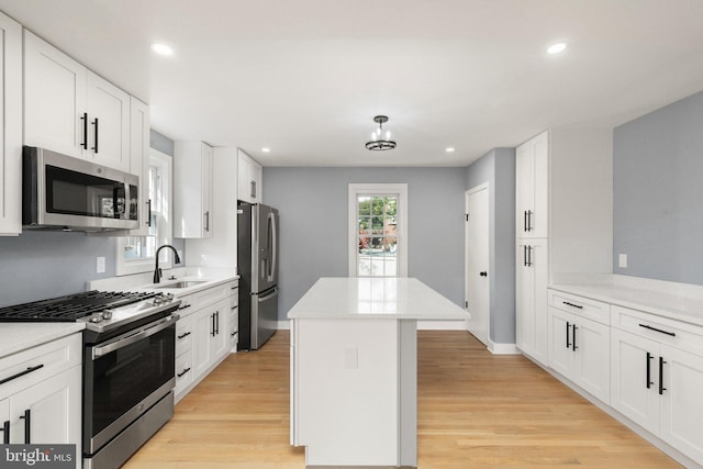 kitchen with white cabinetry, sink, stainless steel appliances, and light hardwood / wood-style floors