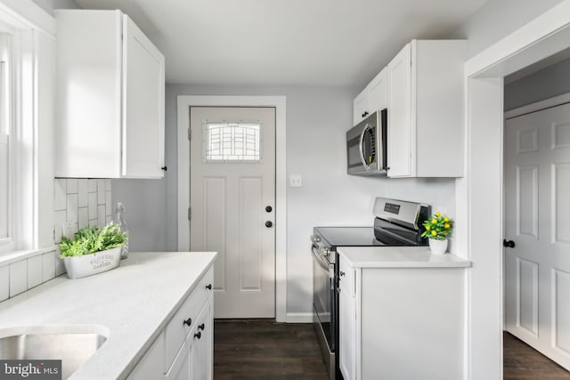 kitchen featuring stainless steel appliances, white cabinetry, and dark hardwood / wood-style floors