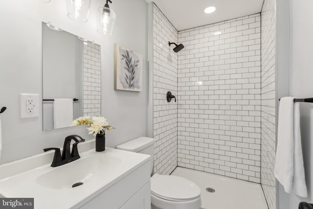 bathroom with vanity, toilet, and tiled shower