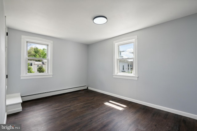 unfurnished room with a healthy amount of sunlight, dark wood-type flooring, and a baseboard heating unit