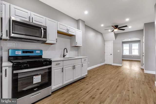 kitchen featuring white cabinets, sink, light wood-type flooring, tasteful backsplash, and stainless steel appliances