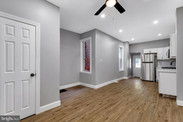 kitchen featuring white cabinets, light wood-type flooring, stainless steel appliances, and ceiling fan