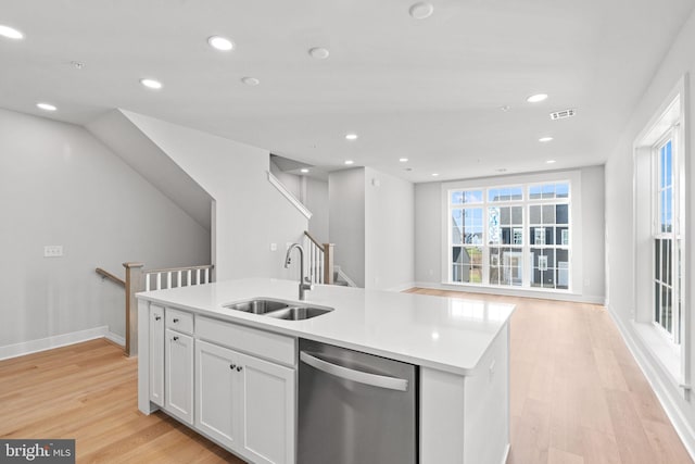 kitchen featuring light wood-type flooring, sink, a center island with sink, dishwasher, and white cabinetry